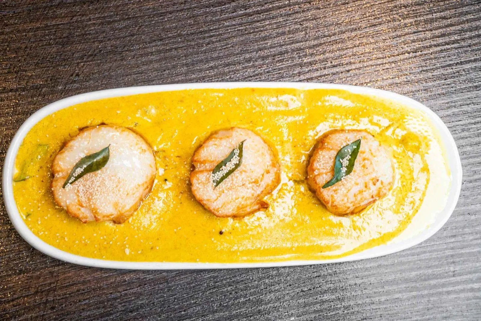 Three dumplings arranged on yellow sauce