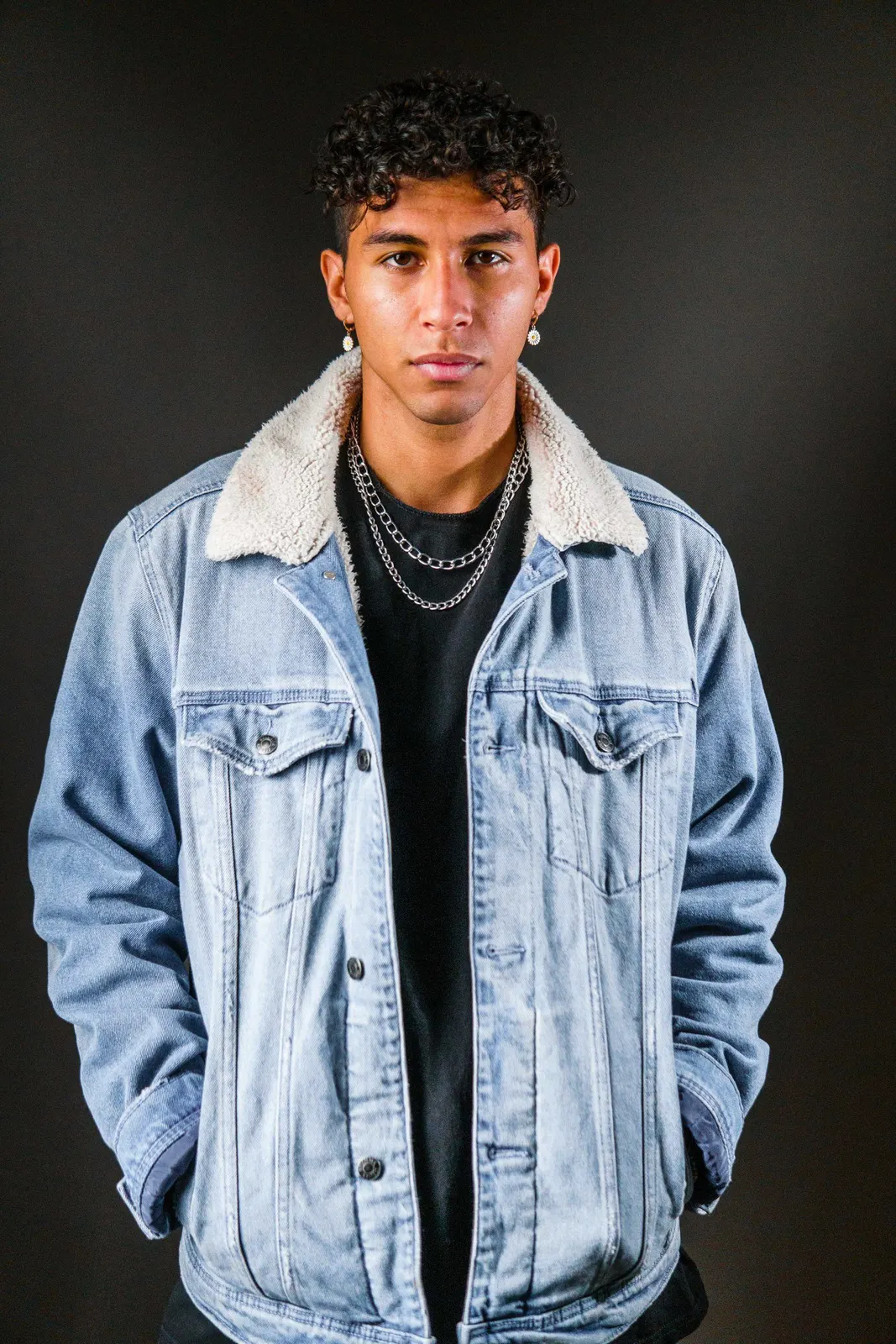 Young man in a denim jacket standing indoors