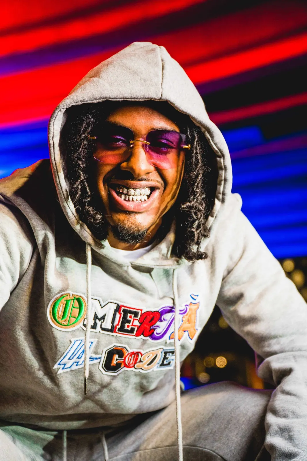 Smiling man in a hooded sweatshirt against colorful lights