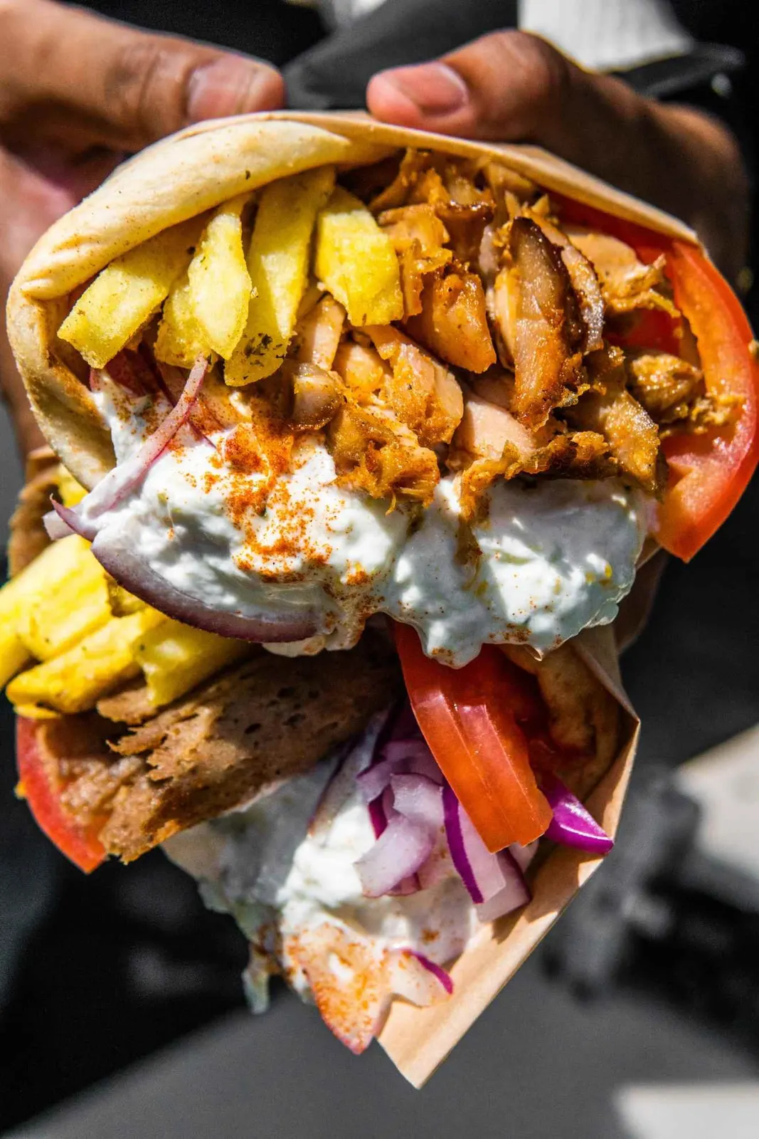 Hand holding a filled pita sandwich