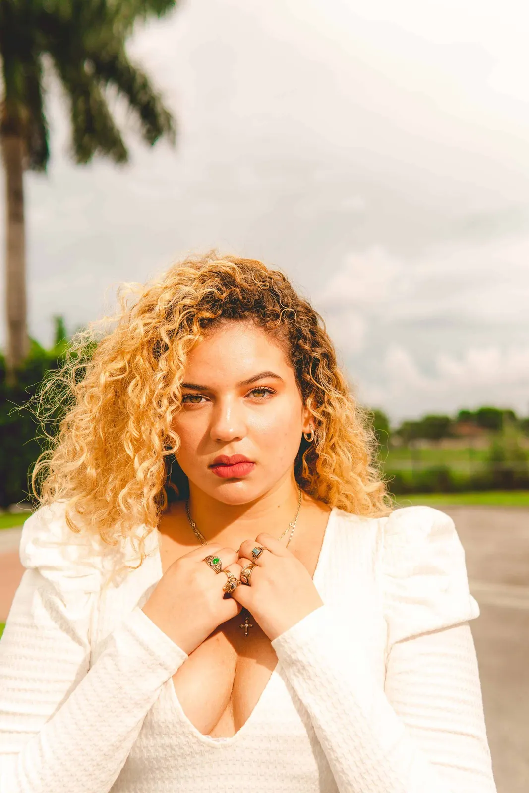 Woman with curly hair in a white shirt outdoors