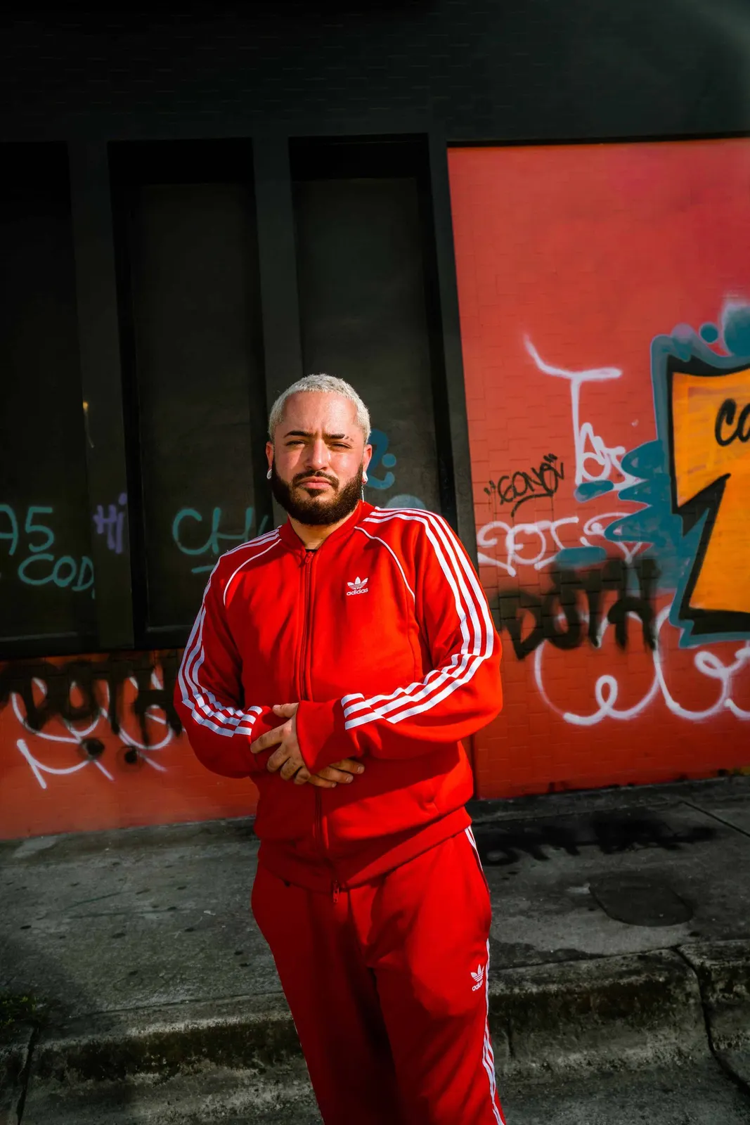 Man in a red tracksuit standing beside a graffiti wall