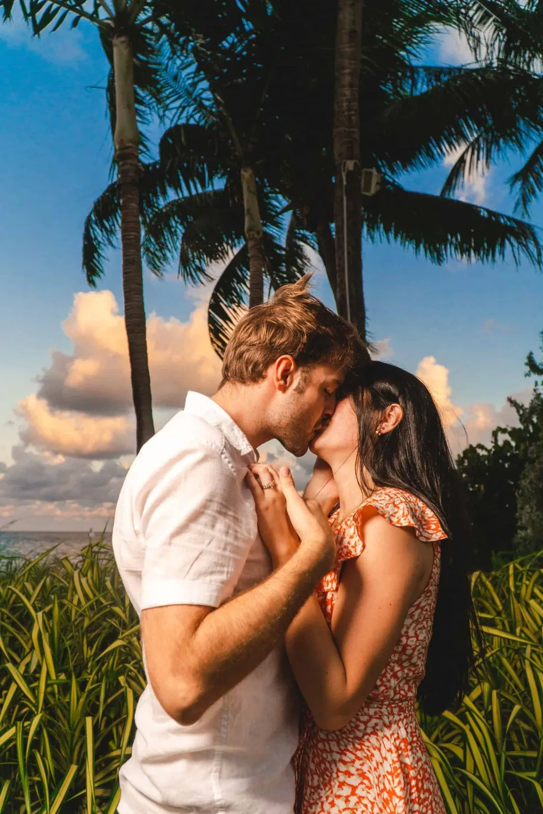 Couple kissing beneath palm trees