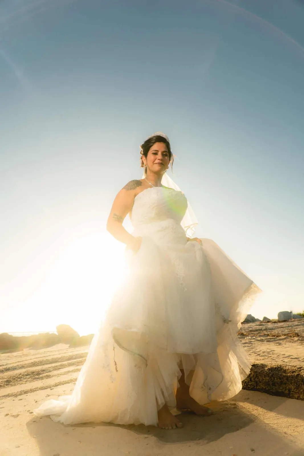 Bride standing on a beach in backlight