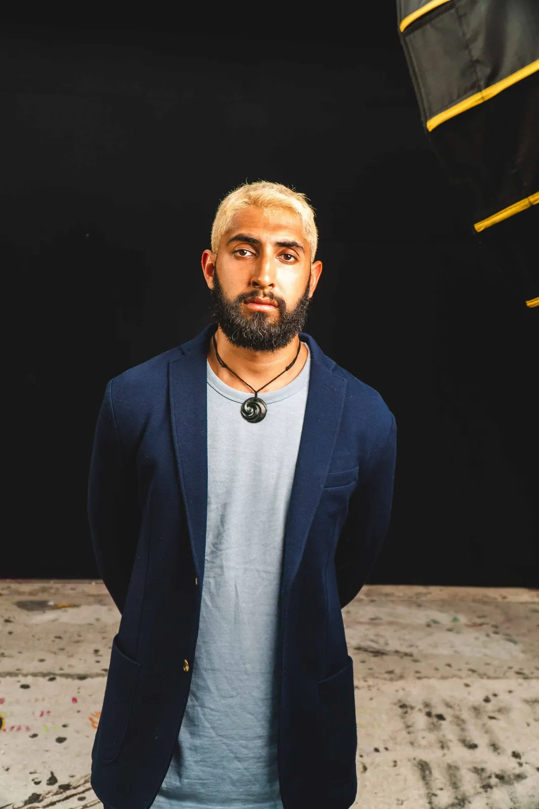 Man in a blazer standing against a dark backdrop