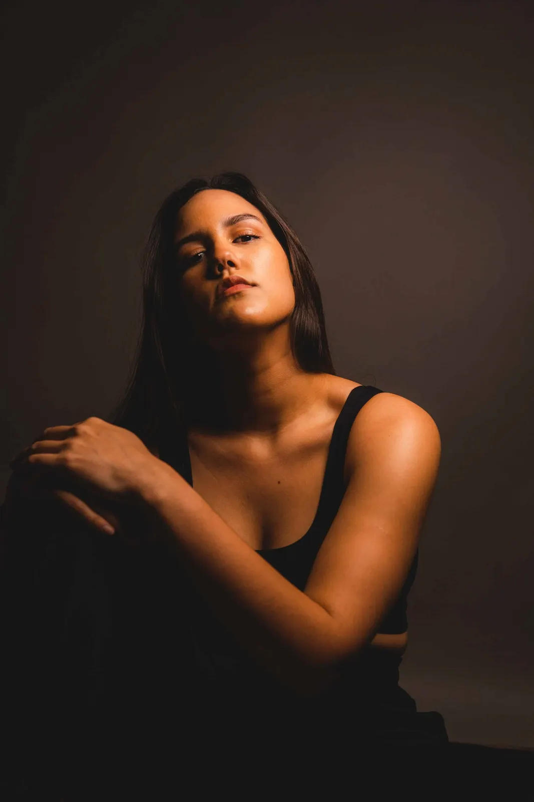Woman in a dark studio portrait with her arms crossed