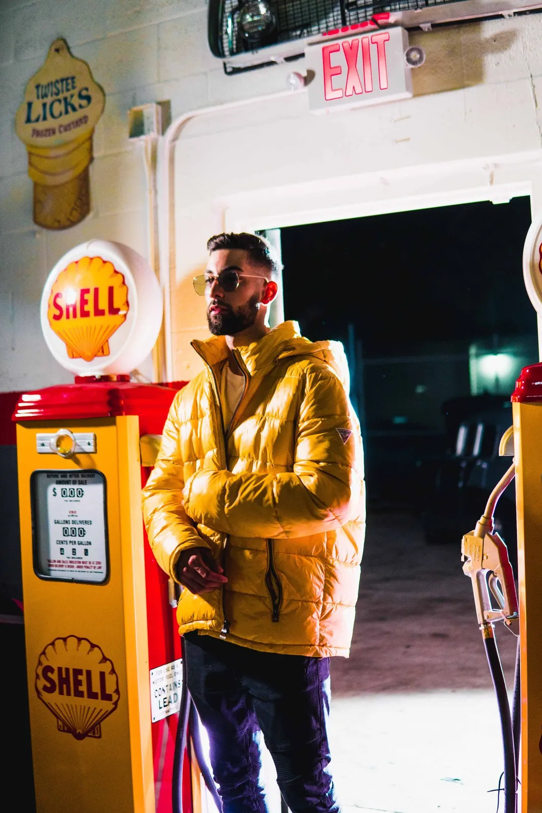 Man in a yellow jacket posing beside a gas station