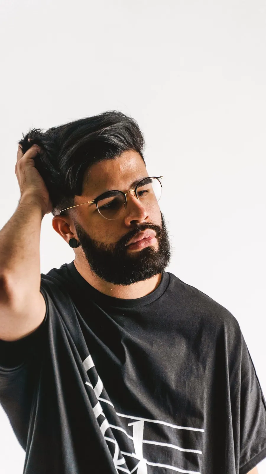 Bearded man adjusting his hair in a studio portrait